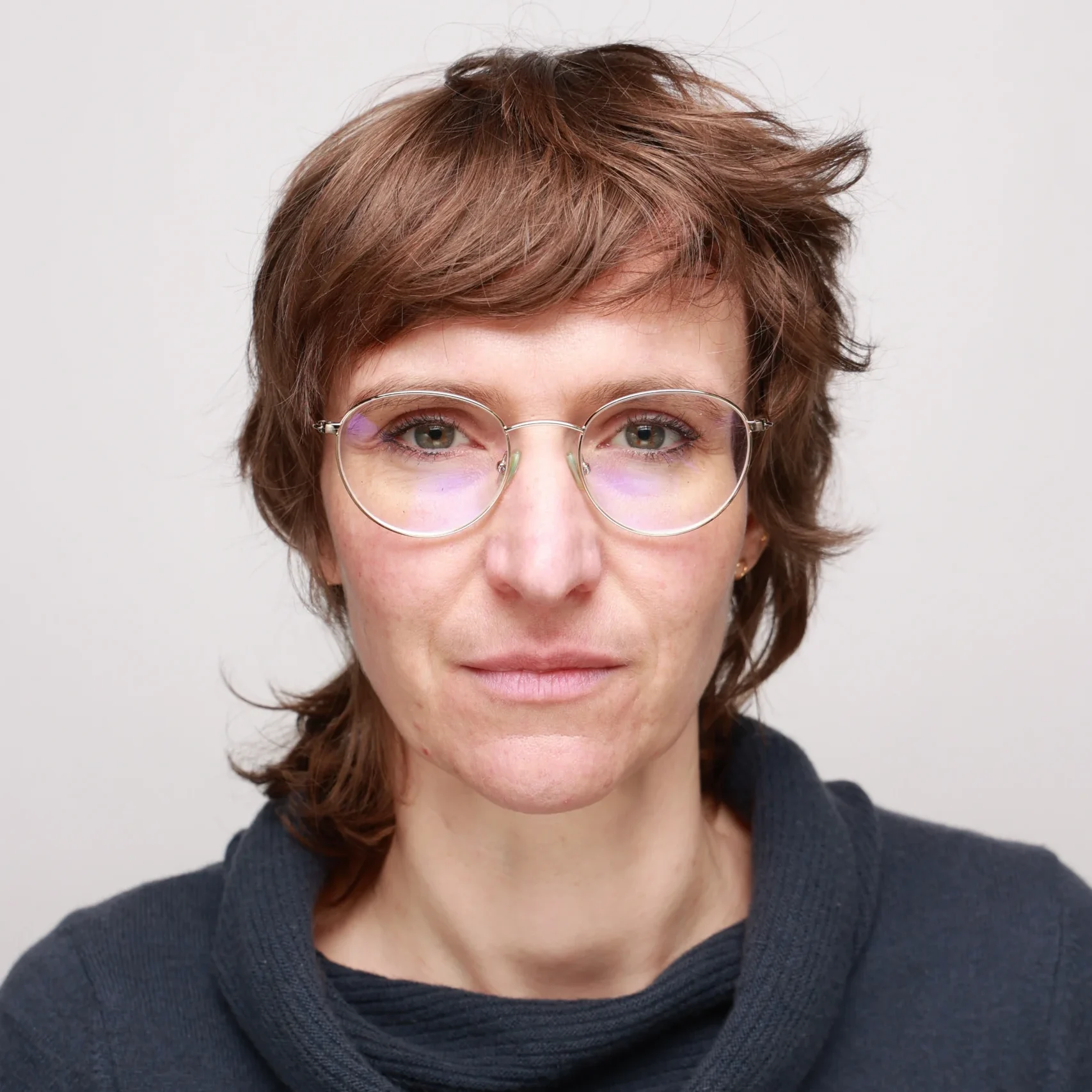 Constanze schaut entschieden und freundlich in die Kamera. Sie hat mittellange braune Haare und trägt eine runde Brille mit dünnem Rand.