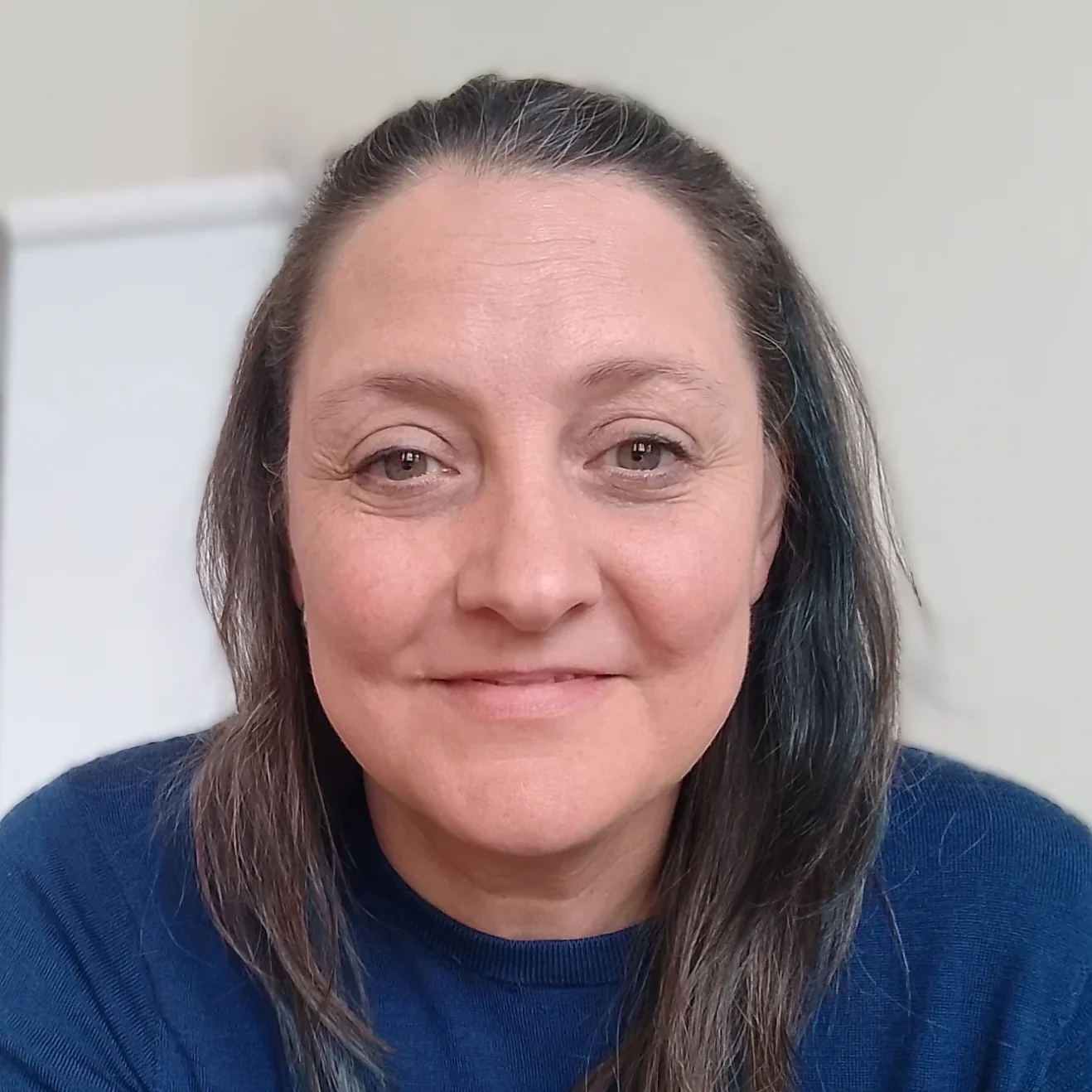 Stephanie schaut lächelnd in die Kamera. Sie trägt einen dunkelblauen Pullover und hat braune Haare mit grauen und blauen Strähnen.