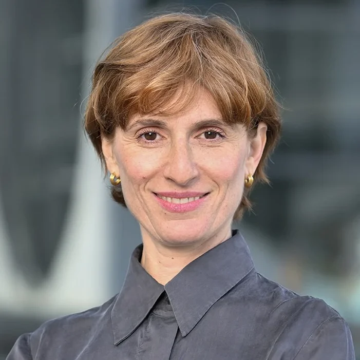 Maja lächelt in die Kamera. Sie hat mittellange, rotbraune Haare und trägt eine dunkelgraue Bluse.